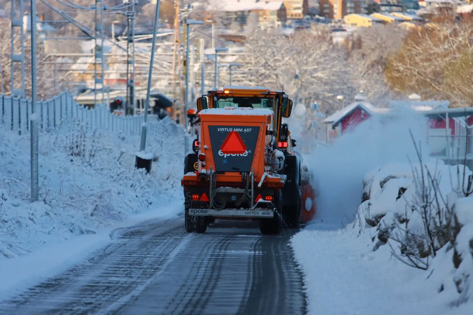 Räumfahrzeug fährt eine verschneite Wohnstraße entlang